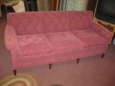 a pink couch sitting in a living room next to a rug