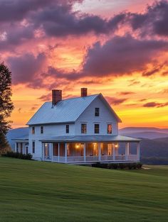 a large white house sitting on top of a lush green field under a cloudy sky