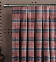 a pink and black plaid curtain hanging from a metal rod on top of a brown wall