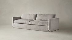 a gray couch sitting on top of a white floor next to a wall with a light colored background