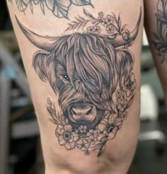 a woman's thigh with a tattoo of a bull and flowers on the side