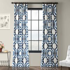 a blue and white curtain with circles on it in front of a chair next to a window