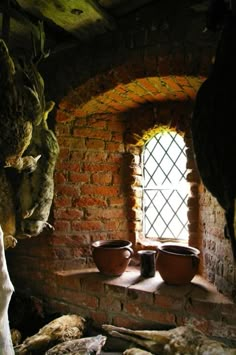 two clay pots sitting on top of a window sill in a brick wall next to rocks