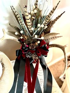 a vase filled with feathers and flowers sitting on top of a white tablecloth covered chair