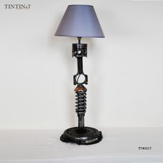 a lamp that is sitting on top of a table next to a white wall with a blue shade