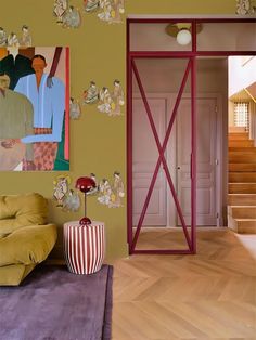 a living room filled with furniture and paintings on the wall next to a stair case