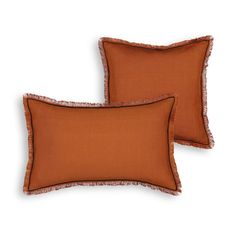 two orange pillows with fringe trims on them