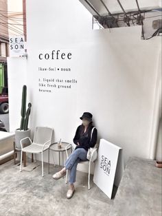 a woman sitting on a chair in front of a coffee sign