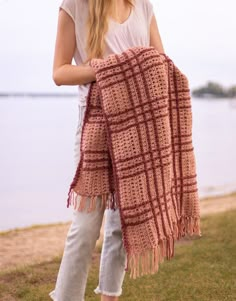 a woman is standing on the beach holding a blanket