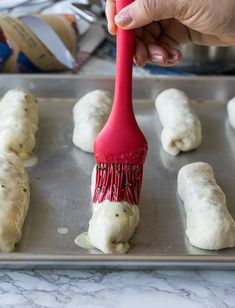 a hand holding a red brush on top of dough