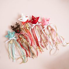 a group of different colored hair clips on a pink surface with bows and reindeer headbands