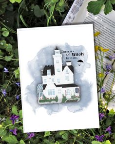 a white card with a castle on it and some flowers in the grass next to it