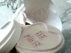 two heart shaped cookies sitting on top of each other next to some paper wrappers