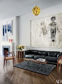 a living room filled with furniture and a large painting on the wall above it's fireplace