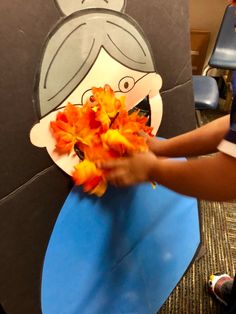 a person holding some flowers in front of a paper cut out of a woman's face