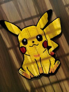 a paper cut out of a pikachu sitting on top of a wooden floor