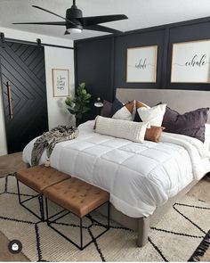 a bedroom with black walls, white bedding and brown foot stools in front of the bed