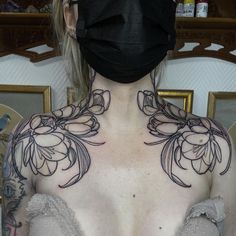 a woman wearing a black face mask with flowers on her chest and neck tattoo design