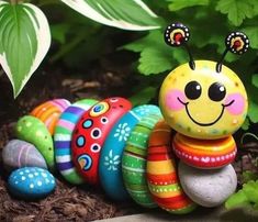 a colorful caterpillar sitting on top of rocks in front of plants and flowers