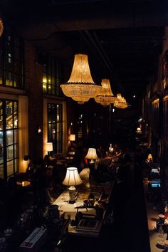 a room filled with lots of furniture and lamps hanging from it's ceiling next to windows