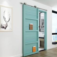 an open blue door in a white room with wood flooring and artwork on the wall