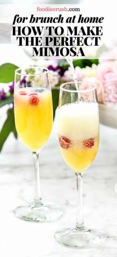 two glasses filled with drinks sitting on top of a white marble counter next to flowers