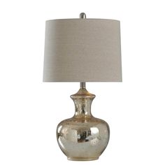 a silver lamp with a white shade on it's base and a beige linen lampshade