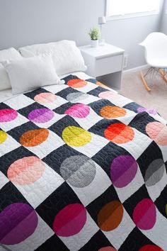 a bed with a black, white and multi colored quilt on it's cover