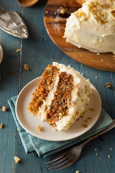 a piece of carrot cake on a plate with a fork next to it and the rest of the cake in the background