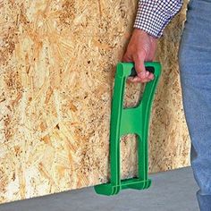 a man is holding a green plastic handrail in front of a plywood wall