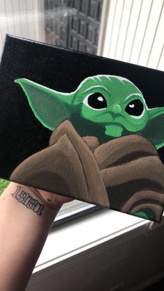 someone holding up a painting of yoda from star wars