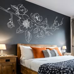 a bedroom with black walls and white flowers painted on the wall above the headboard