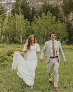 a bride and groom are walking through the grass holding each other's hands as they walk