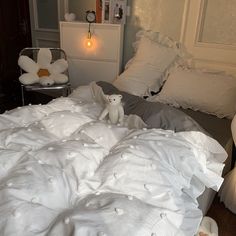 a white teddy bear sitting on an unmade bed