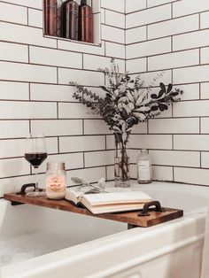 a bathtub with a book, glass of wine and vase