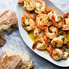 a white plate topped with shrimp next to bread