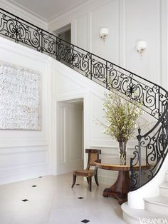 an elegant staircase with wrought iron railing and handrail in a white house, leading up to the second floor