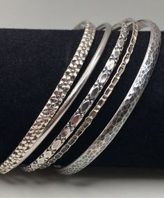 Here are 5 beautiful Pieces Bangles set come with 5 different beautiful patterns. Some bangles are DANCECRAFT .  Wear those 5 together is made you very special. Great pre-own condition. All bangles Stamped "Sterling" or "925" mark inside the bangles. Bangle Measures around: 8 1/2" -8 3/4"  (21.6 cm - 22 cm) 5 Bangles width:  2 mm - 5 mm Total Weight: 36 grams (1.2 Troy Oz)  Item is exactly as shown in pictures.    Please carefully review the item description and accompanying pictures before making a purchase, as we do not offer a return or exchange policy. If you have any questions or require assistance, please do not hesitate to reach out to us.  Check my store link to find more treasures:   https://galaxysilvercity.etsy.com Handcrafted Silver Bangle, Antique Silver Bangle For Festive Occasions, Festive Silver Hallmarked Bangle, Antique Silver Nickel-free Bangle Bracelet, Bangles Silver, Vintage Silver Bangle, Collectible, Vintage Sterling Silver Bangle, Hallmarked, Bangles Set, Multi Pattern