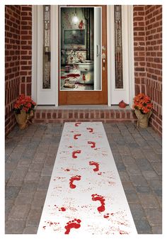 a white rug with red paint on it sitting in front of a door and some potted plants