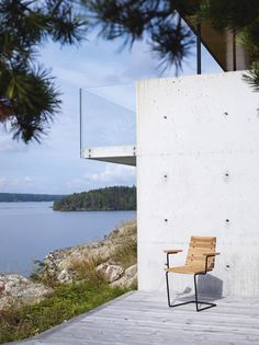 a wooden chair sitting on top of a wooden floor next to a building near the water