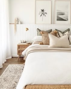 a bed with white sheets and pillows in a bedroom next to two pictures on the wall