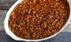 a white bowl filled with baked beans on top of a wooden table