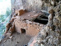 an old building built into the side of a mountain with rocks and dirt around it