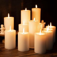 many lit candles sitting on top of a wooden table