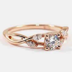 a rose gold ring with three diamonds on the band and an oval shaped center stone