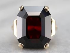 This classic garnet ring certainly commands one's attention. The simple polished yellow gold mounting allows plenty of light to reach the center and sides of the stone, giving the garnet a burst of rich, blood-red coloring. This is definitely a bold statement piece! Metal: 10K Yellow Gold Gem: Garnet 19.73 (approximately) Gem Measurements: 13.8 x 17.0 mm, Cushion Cut Ring Size: 6 Marks: "10K" Stamped on the inside band Yellow Gold Sapphire Ring, Demantoid Garnet, Garnet Gem, Cushion Cut Ring, Garnet Ring, Blood Red, July Birthstone, Garnet Rings, Cocktail Ring