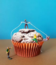 a cupcake with two figurines on top of it and one being held by a wire