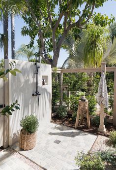 an outdoor shower in the middle of a garden area with trees and plants around it