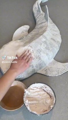 someone is painting a dolphin on the floor with white paper and brown liquid in a bowl