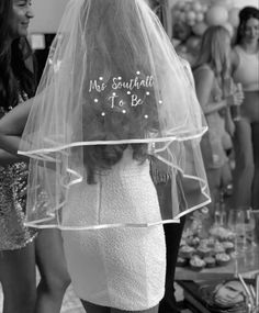 a woman with a veil on her head is standing in front of other women at a party